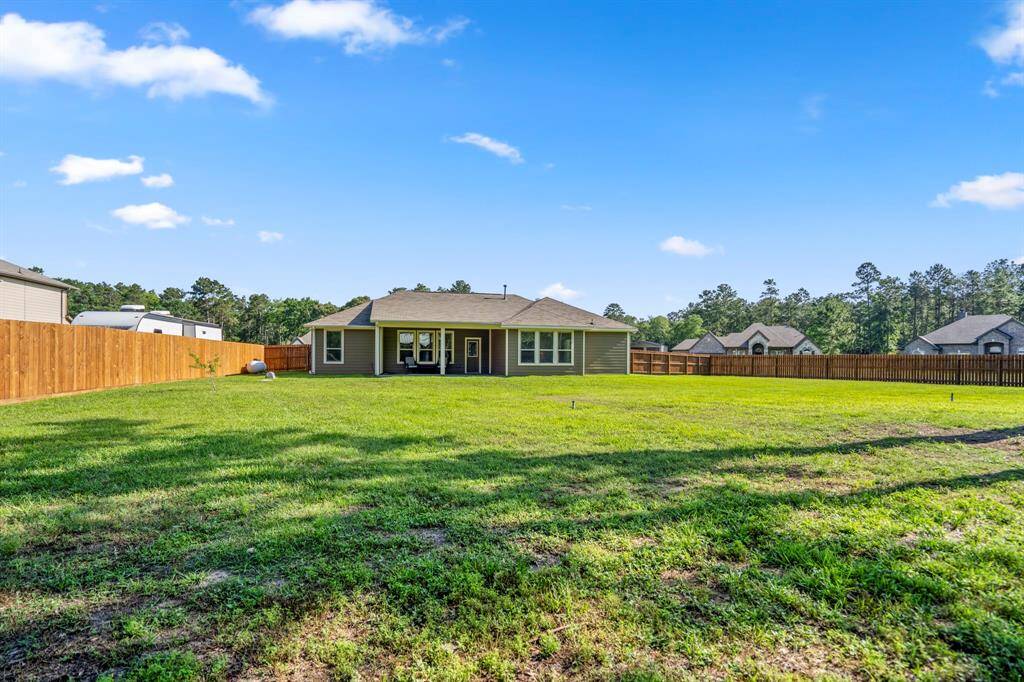 From further back in the yard, we see the home with its expansive, lush green lawn, all kept vibrant by the irrigation system, offering plenty of space to enjoy the outdoors.