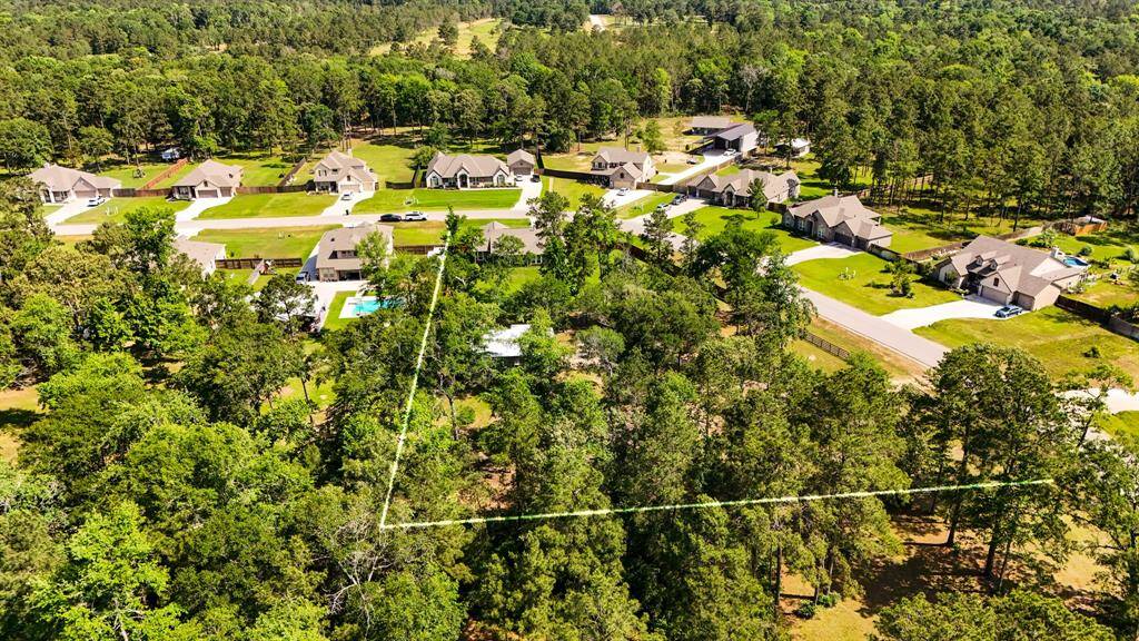 This view from directly behind the home gives another perspective of the spacious backyard and surrounding trees, highlighting the sense of privacy and open space that comes with country living on a corner lot.