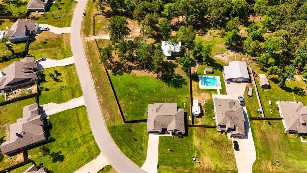 This aerial view from the street in front of the home provides a clear look at the home's position on the corner lot, the surrounding trees, and the spacious yard wrapping around the property.
