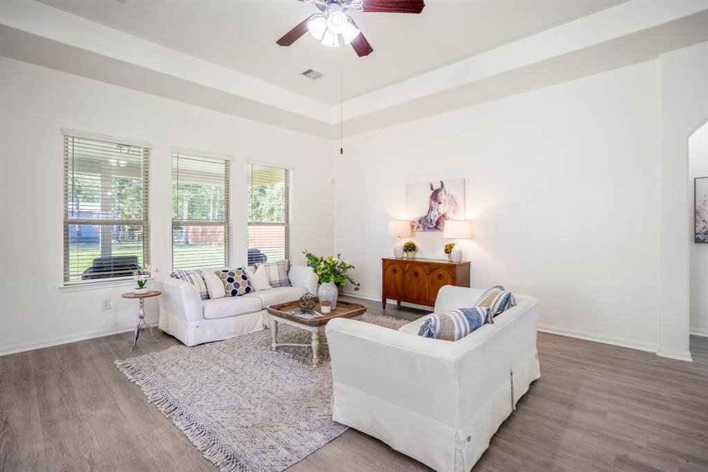 Another view of the living room showcases the abundance of natural light streaming in, highlighting the raised ceilings and durable vinyl plank flooring that flows throughout the space.
