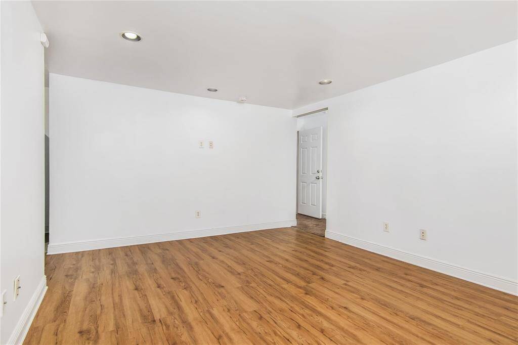 Spacious living area on the first level of the duplex, featuring sleek hardwood floors and modern recessed lighting.