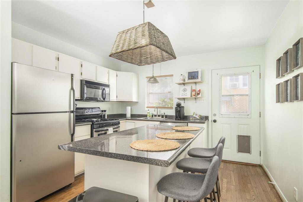 Charming cottage kitchen featuring modern appliances, a spacious countertop island, and cozy seating for four.