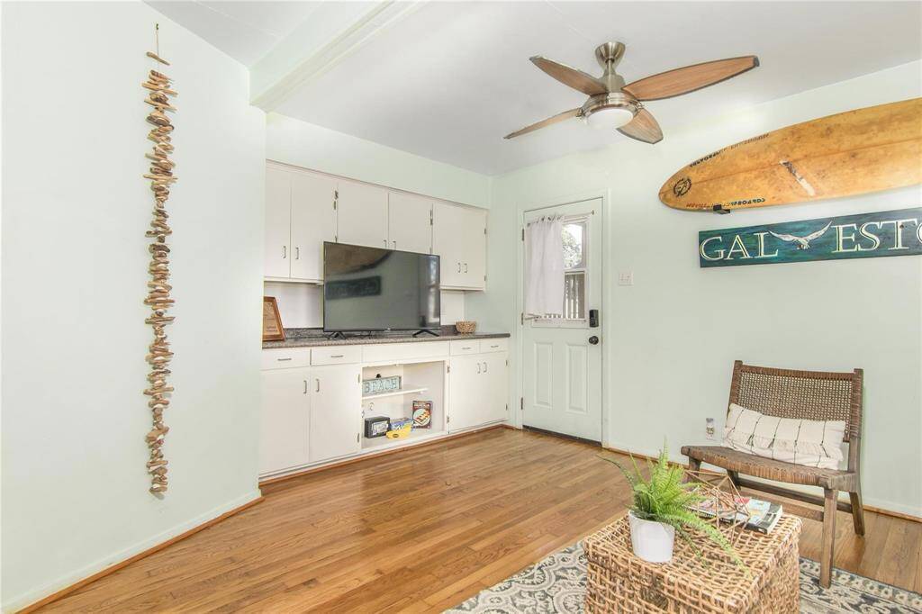 Cozy cottage living area featuring charming coastal decor, wood floors, and a built-in entertainment center. Perfect for relaxing or entertaining.