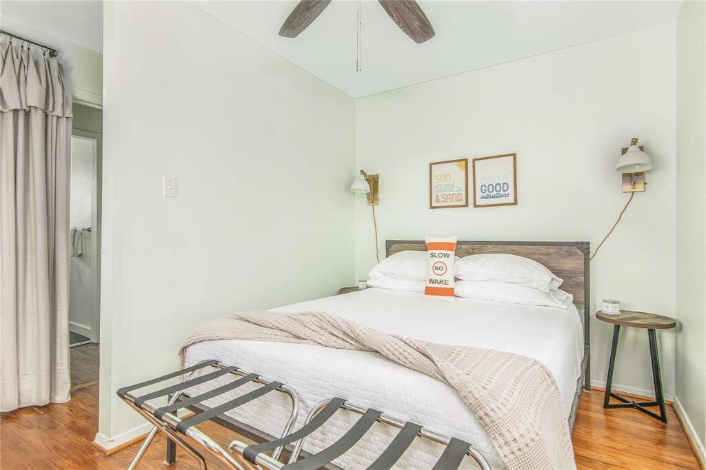Charming primary bedroom in a cozy cottage, featuring a serene color palette, contemporary lighting, and inviting decor for a peaceful retreat.