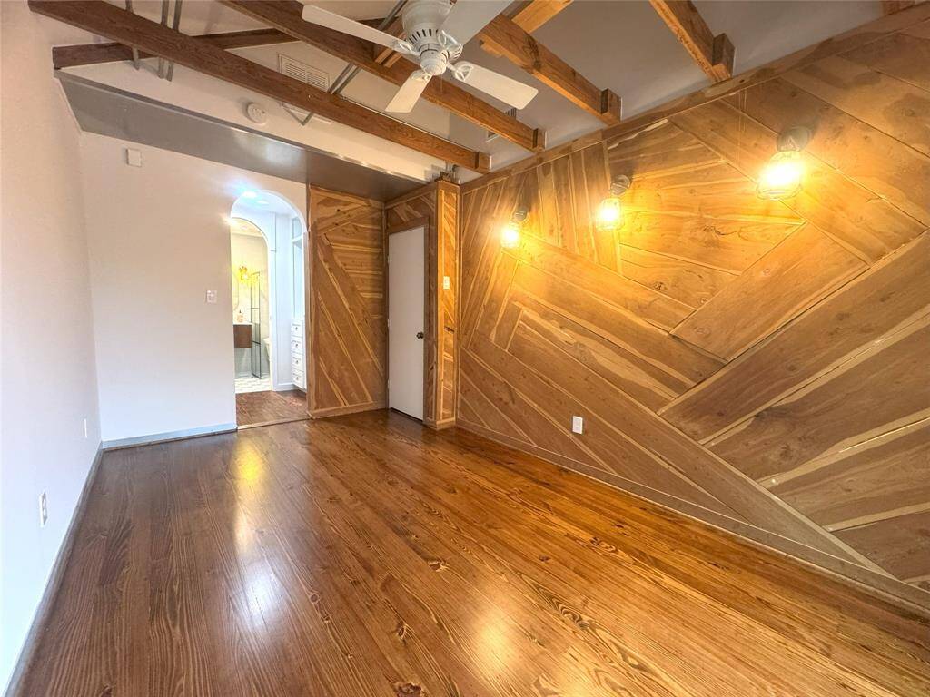 Primary bedroom with High ceiling, wood accent wall, original wood floor and en- suite bathroom.