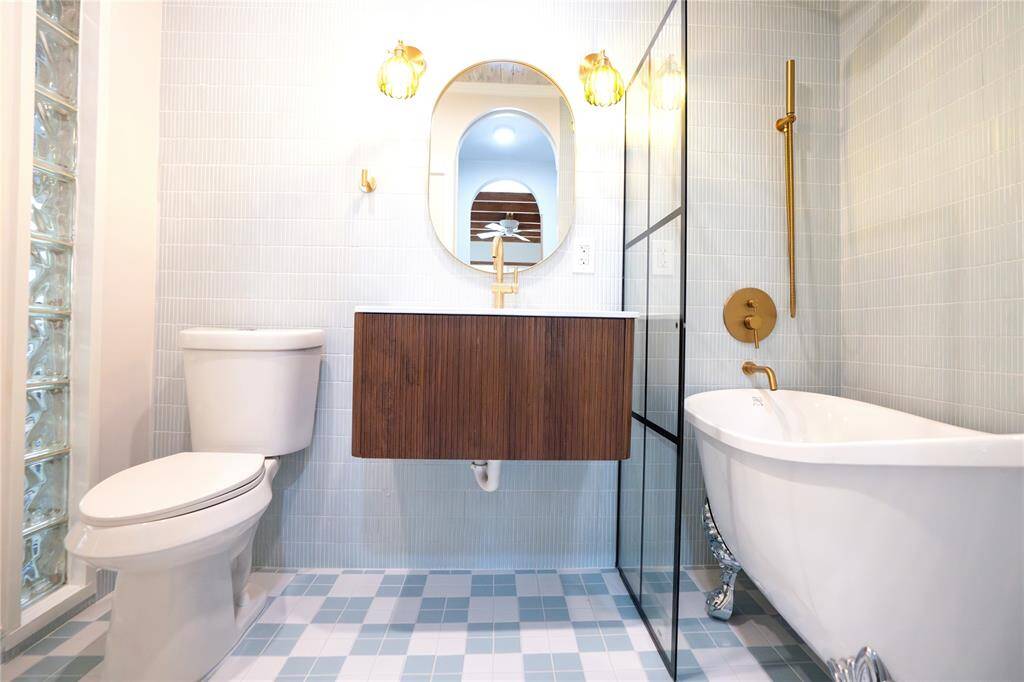Elegant primary bathroom with modern vanity, free-standing tub, light fixtures, designer flooring!