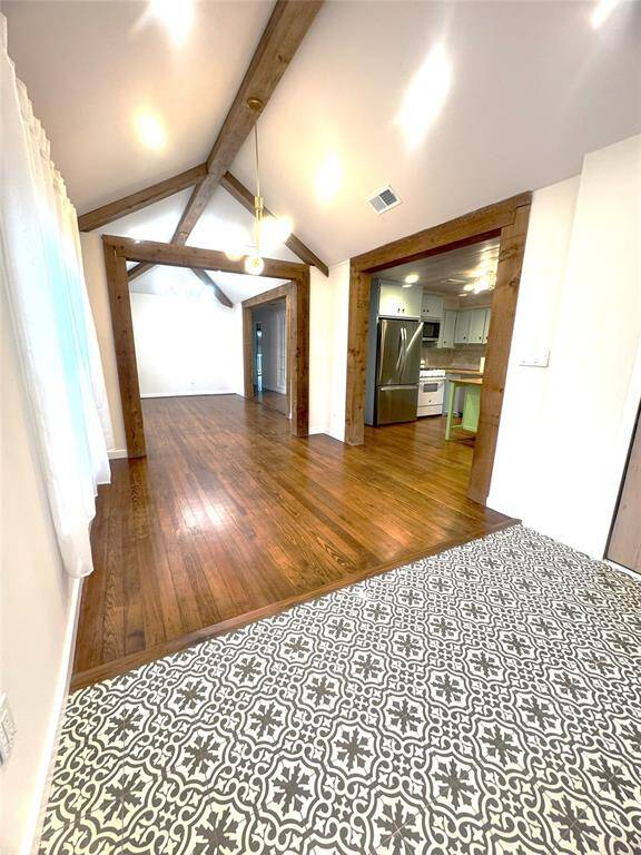 This beautiful living and dining room has a vaulted ceiling with wood beams and original wood flooring.