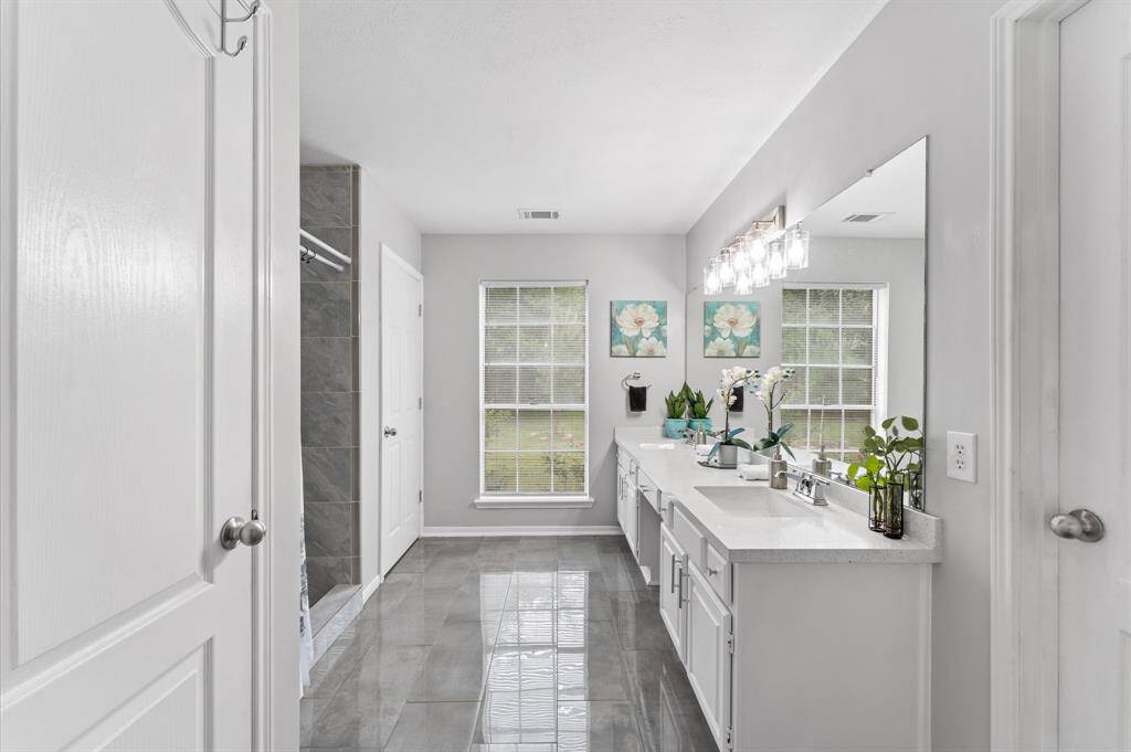 The serene primary suite boasts a spa-like en-suite bathroom with luxurious walk-in shower, sleek tilework, and a walk-in closet.