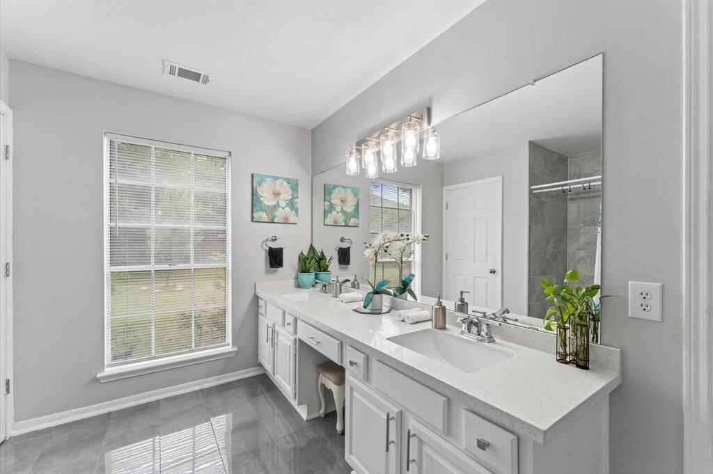 The serene primary suite boasts a spa-like en-suite bathroom with luxurious walk-in shower, sleek tilework, and a walk-in closet.