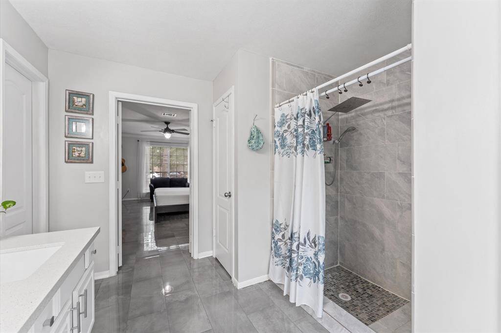 The serene primary suite boasts a spa-like en-suite bathroom with luxurious walk-in shower, sleek tilework, and a walk-in closet.