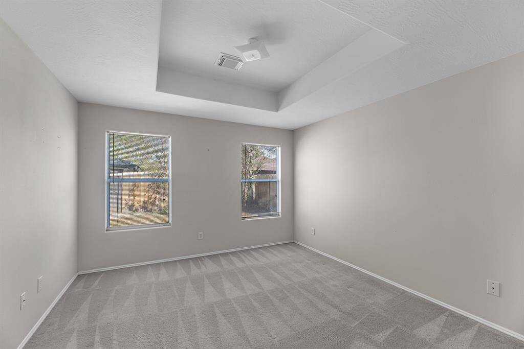 The primary bedroom has tray ceilings
