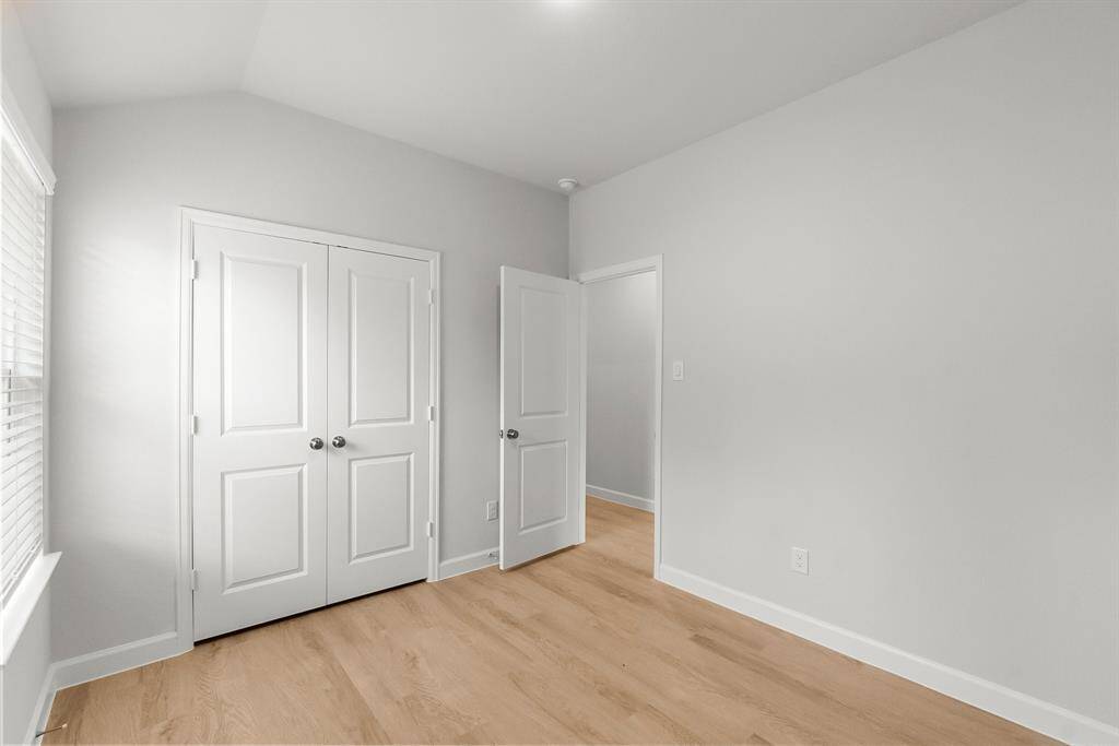 Bright and inviting, this cozy room features light wood flooring and neutral walls. It includes a spacious double closet and a window that bathes the space in natural light, perfect for a bedroom or home office.
