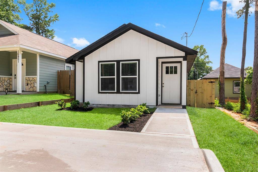 Charming single-story home with a sleek black-and-white design, featuring a beautifully landscaped front yard and a welcoming pathway. Perfect for cozy living.