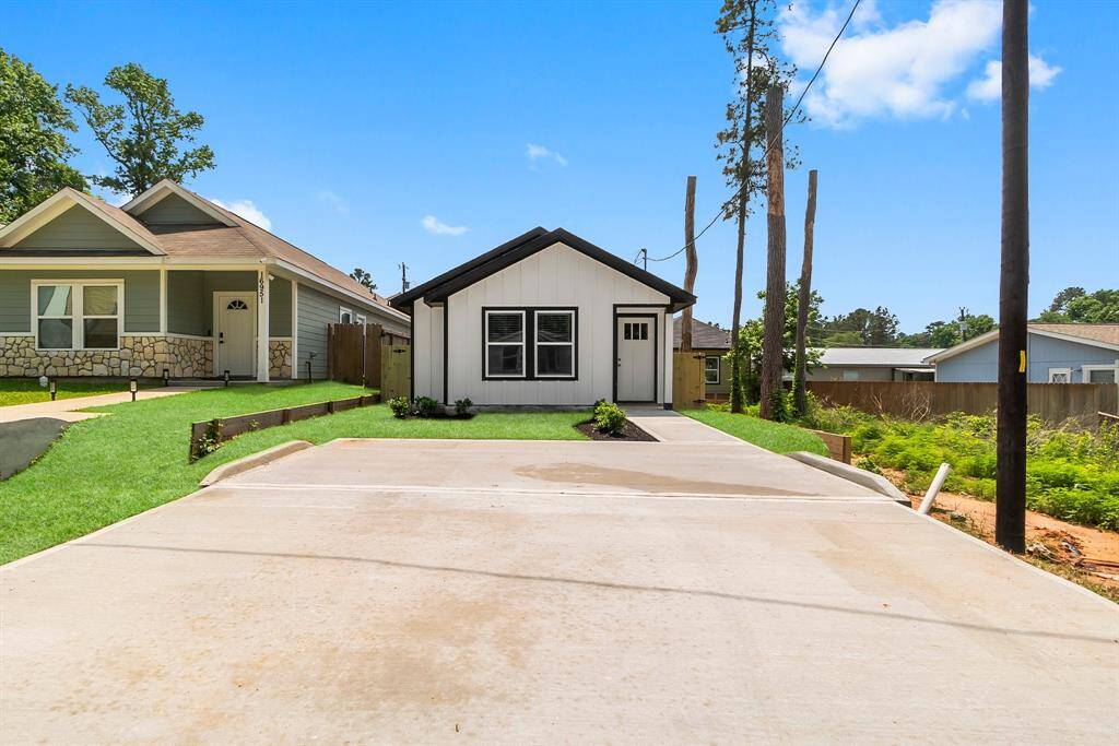 Charming modern single-story home with a sleek white exterior, black trim, and a pristine driveway.