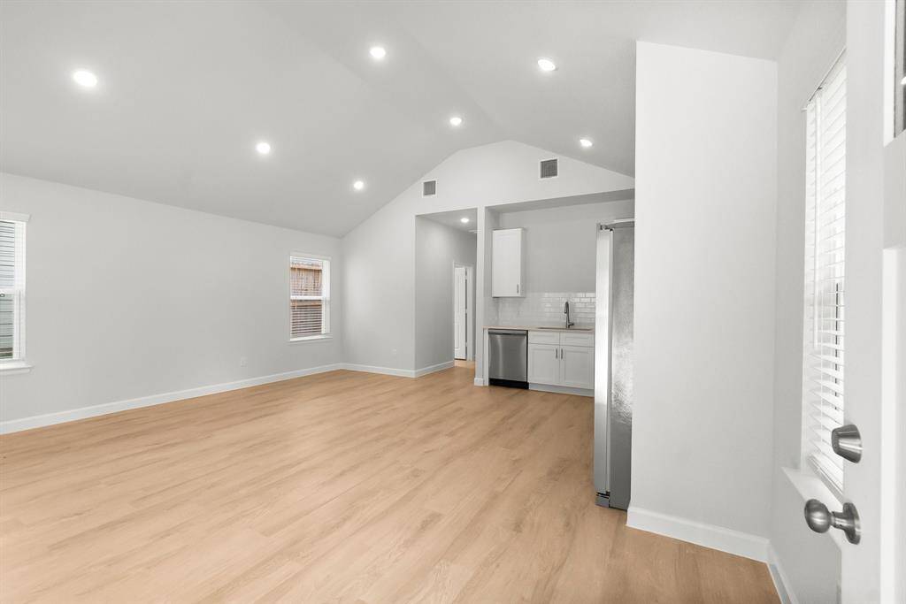 Experience modern living in this bright, open-concept space with high ceilings and recessed lighting. Enjoy light wood floors and large windows that flood the area with natural light. The sleek kitchen features white cabinetry, a stainless steel fridge, and a stylish backsplash.