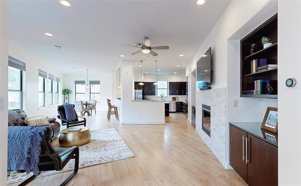 This modern living space features a sleek fireplace. The area is flanked by built-in dark wood shelves and cabinets, offering ample storage.