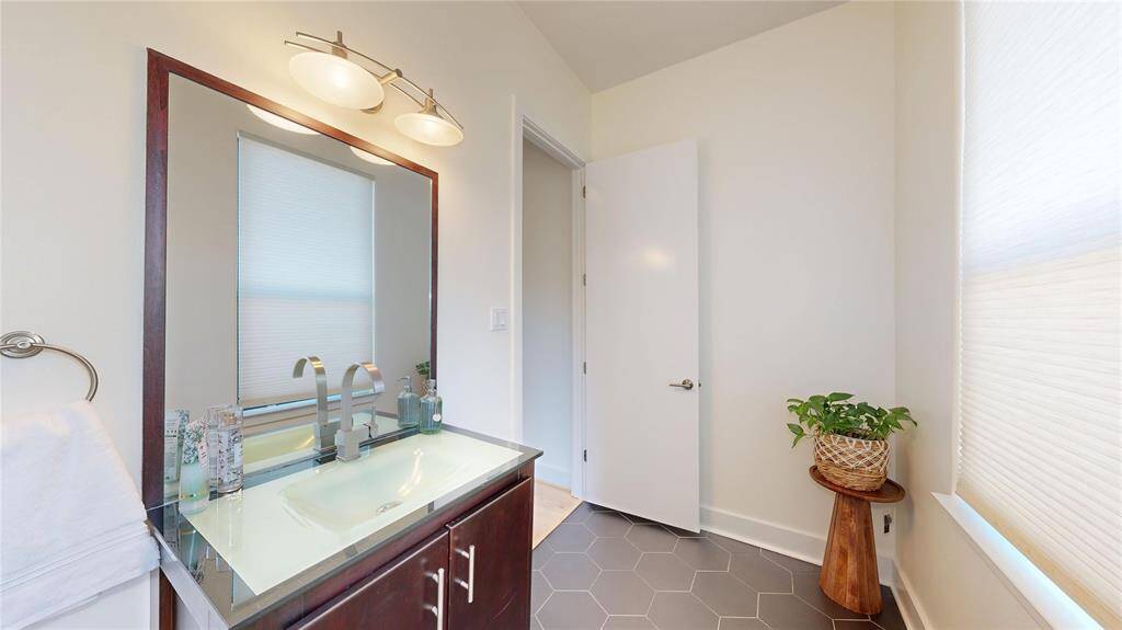 Powder Room is on the main floor and features a modern design with hexagonal floor tiles, and a sleek vanity with glass countertop.