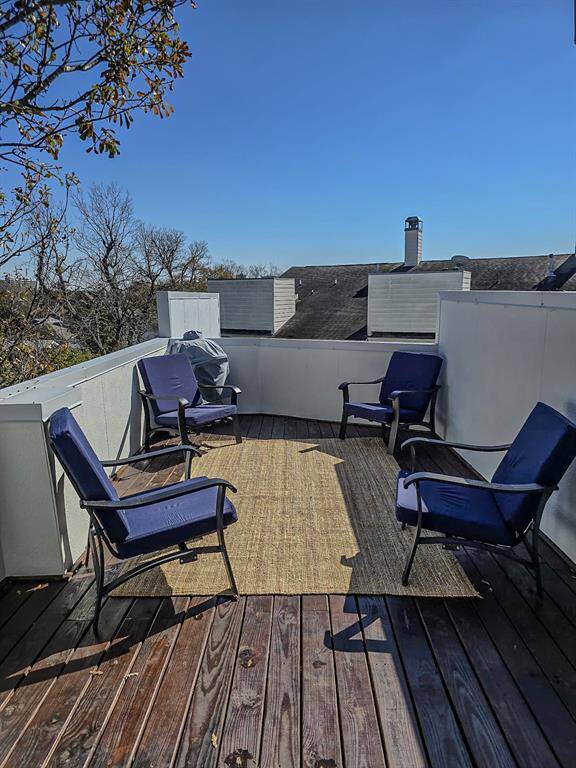 This photo showcases a spacious rooftop deck with wooden flooring surrounded by a scenic view of nearby trees and rooftops, perfect for entertaining or relaxing.