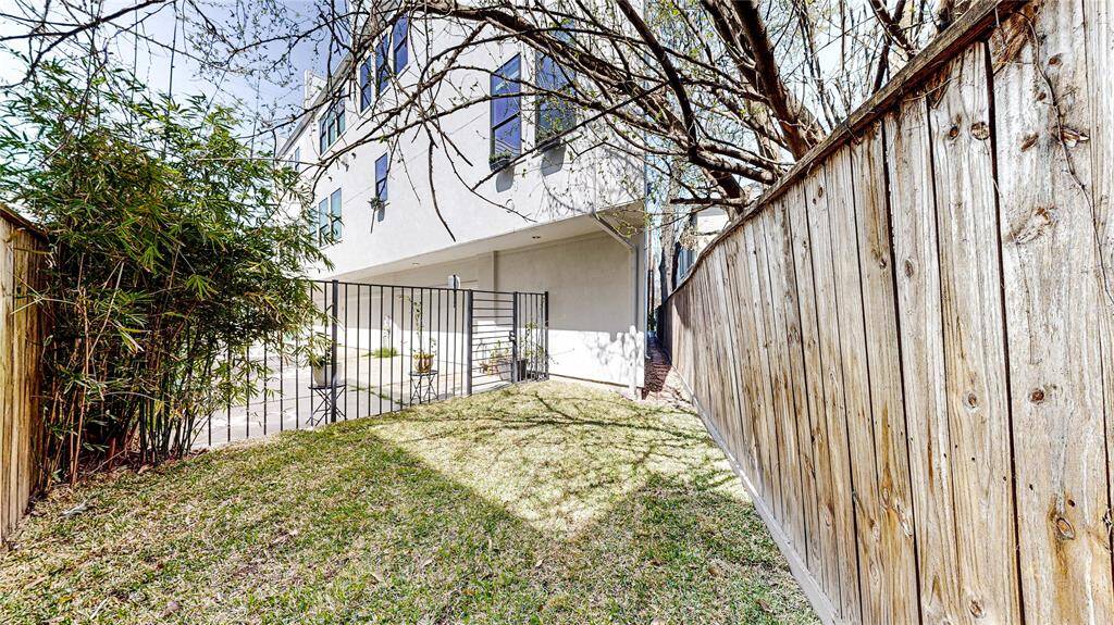 This photo showcases the outdoor space, that is fully fenced, offering a private spot ideal for relaxation or minimalist gardening.