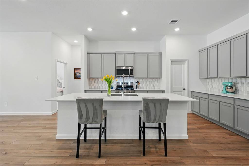 The kitchen features a large island, plenty of storage space, and sleek quartz countertops, making it both functional and stylish.