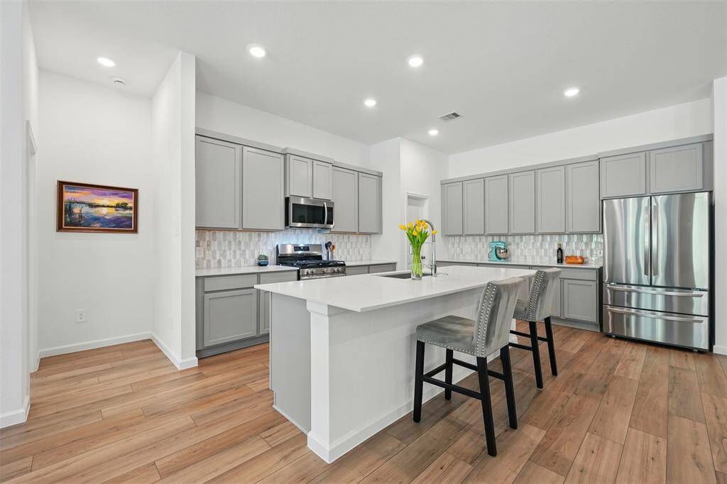 The kitchen features a large island, plenty of storage space, and sleek quartz countertops, making it both functional and stylish.