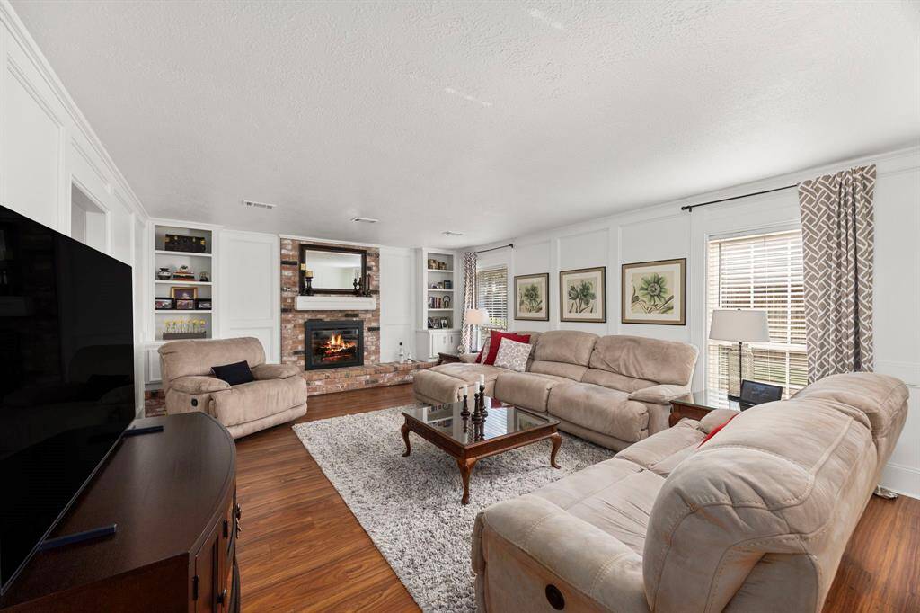 Large family room features brick fireplace with gas logs and built-ins