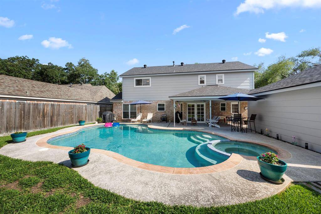 Rear view showing sparkling pool and spa, covered patio