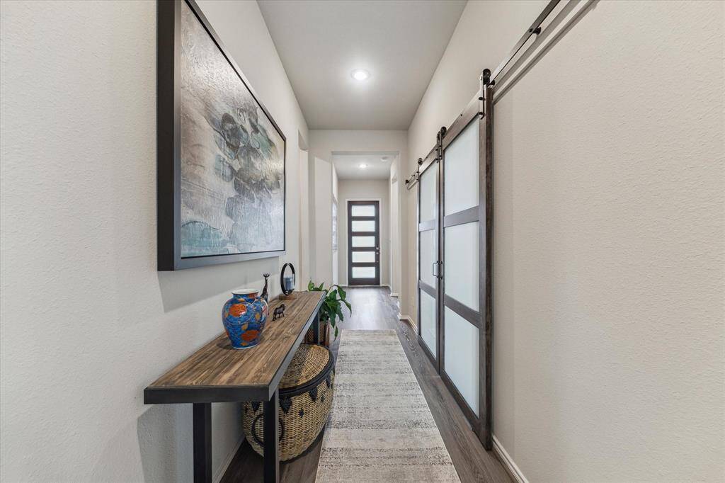 This inviting foyer makes a stylish first impression, featuring warm LVP flooring, soft neutral tones, and modern glass sliding doors that hint at the thoughtful design found throughout the home. From the moment you step inside, it feels both polished and welcoming.