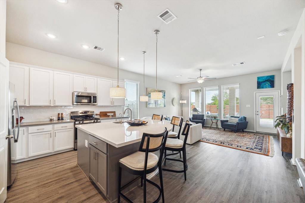 This open floor plan offers a seamless flow, with an elegant dining area and an island kitchen with bar seating that open directly to the family room, creating a warm, connected space for everything from quiet evenings to lively gatherings.