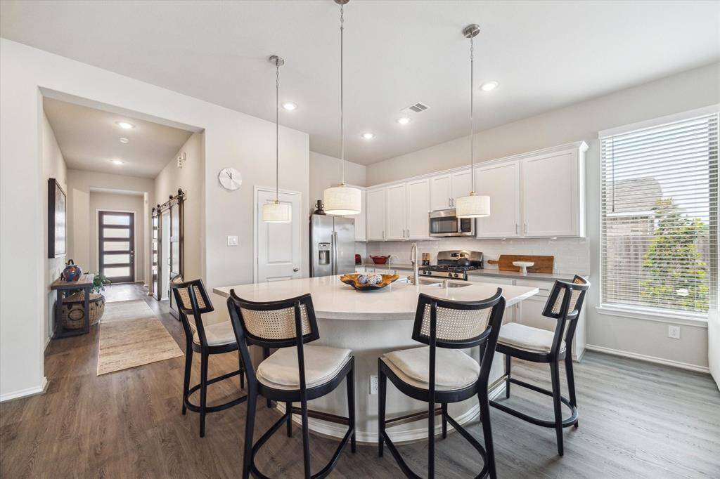 A large center island with bar seating and chic overhead lighting anchors the space, offering a seamless connection to the family room and dining area. It's perfect for cooking, gathering, and entertaining.