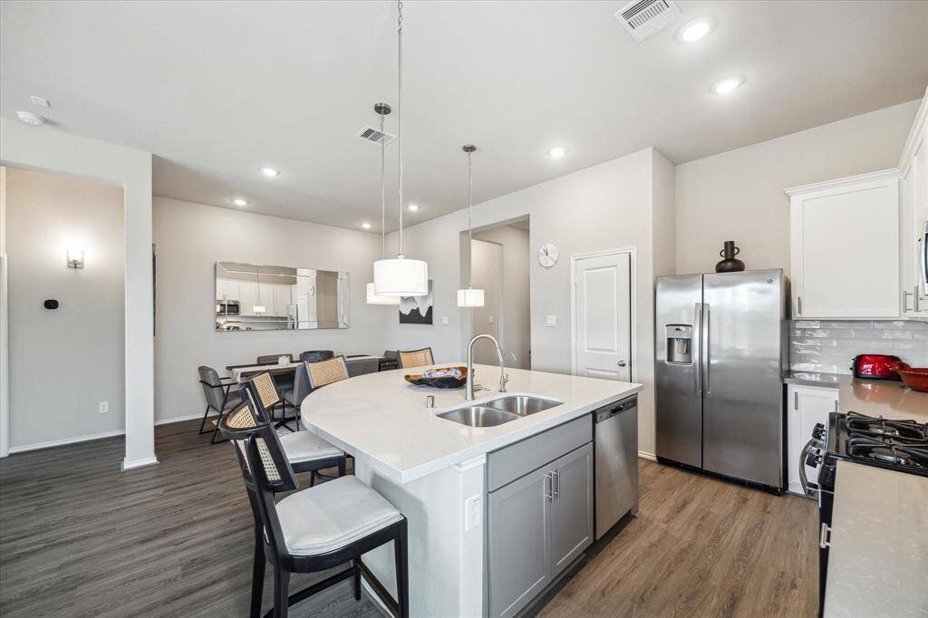 Show off your culinary skills in this stunning island kitchen, featuring OmegaStone countertops, subway tile backsplash, stainless steel appliances, under-cabinet lighting, and a spacious island with bar seating and chic pendant lights. With a walk-in pantry, and plenty of space for meal prep and cleanup, this kitchen is built for both convenience and style.