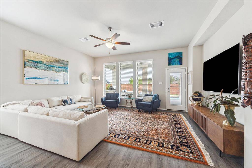 The spacious family room is filled with natural light from a wall of windows overlooking the covered patio and pool. With LVP flooring, neutral paint, and recessed lighting, it’s the perfect place to gather, unwind, and make lasting memories.