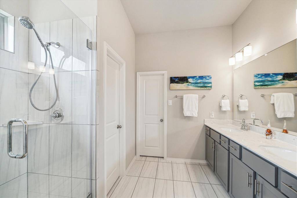 This luxurious ensuite bathroom has everything you need to start the day right, including a dual-sink vanity, a spacious walk-in shower, and a private water closet.