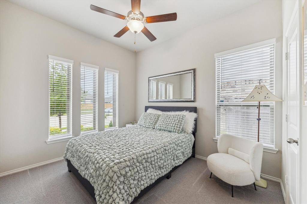 Family and guests will rest comfortably in this spacious guest bedroom featuring soft neutral finishes, a cooling ceiling fan, a large closet, and easy access to a full bathroom.