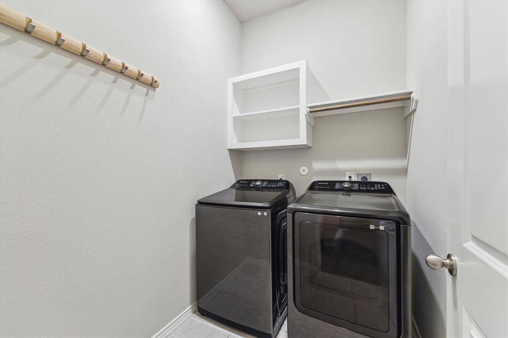 Laundry will be a snap with the help of this spacious utility room with built-in shelving for household storage and a hanging bar for clothes.