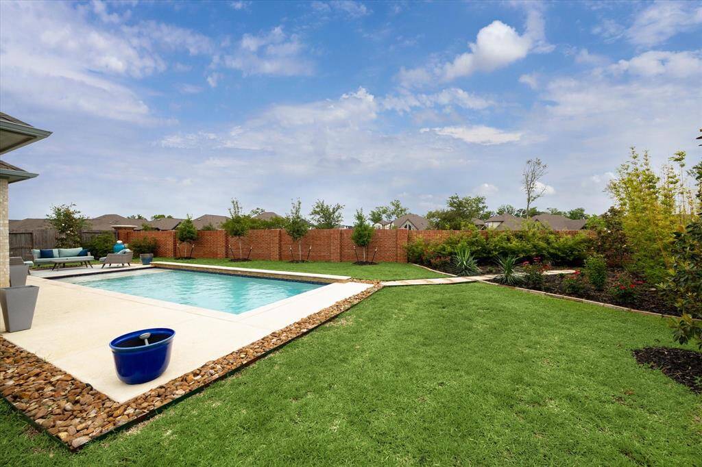 The expansive backyard is a true retreat, featuring 4 Holly trees, 7 Magnolia trees, a lush garden, and plenty of grassy space for barefoot fun.