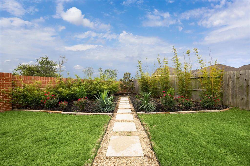 Follow the stone path to a beautifully landscaped garden bursting with color and texture. Filled with vibrant blooms and lush greenery, this tucked-away haven adds a sense of calm and natural beauty to your backyard retreat.