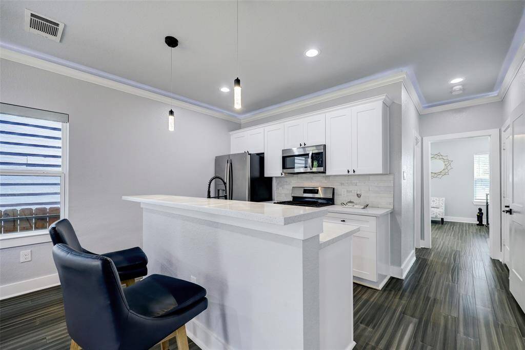 Kitchen with breakfast bar and stainless appliances. Photos are staged. Property comes unfurnished.