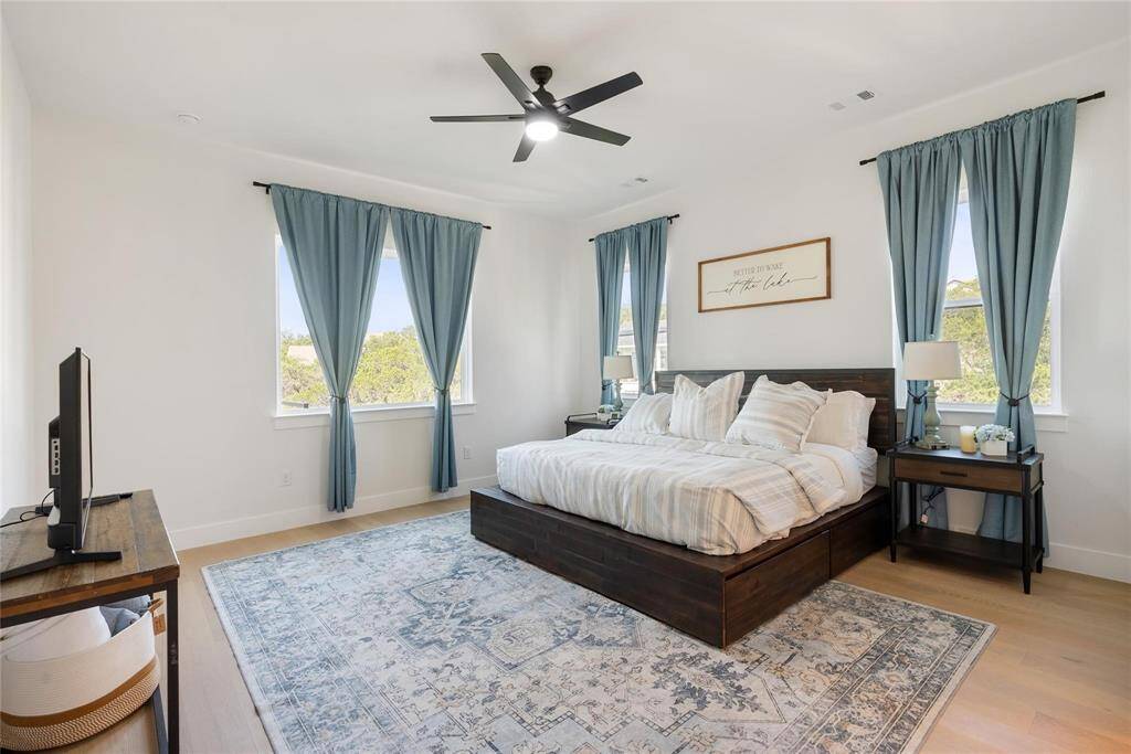 Large primary bedroom with 10" tray ceiling and light wood flooring