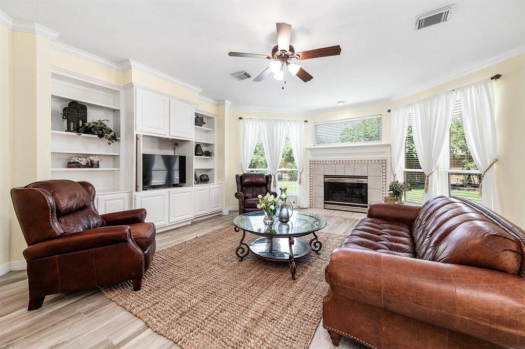 This spacious den features built-in bookcases and a gas-log fireplace, framed by windows with backyard views.