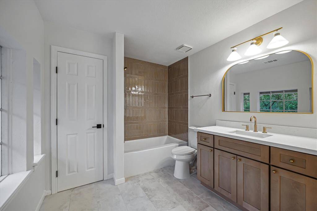 BIG SECONDARY BATHROOM UPDATED WITH TILE FLOORING, VANITY, TILE TUB SURROUND, TOILET, LIGHTING, COUNTER, AND MIRROR. ALL DONE FOR YOU!