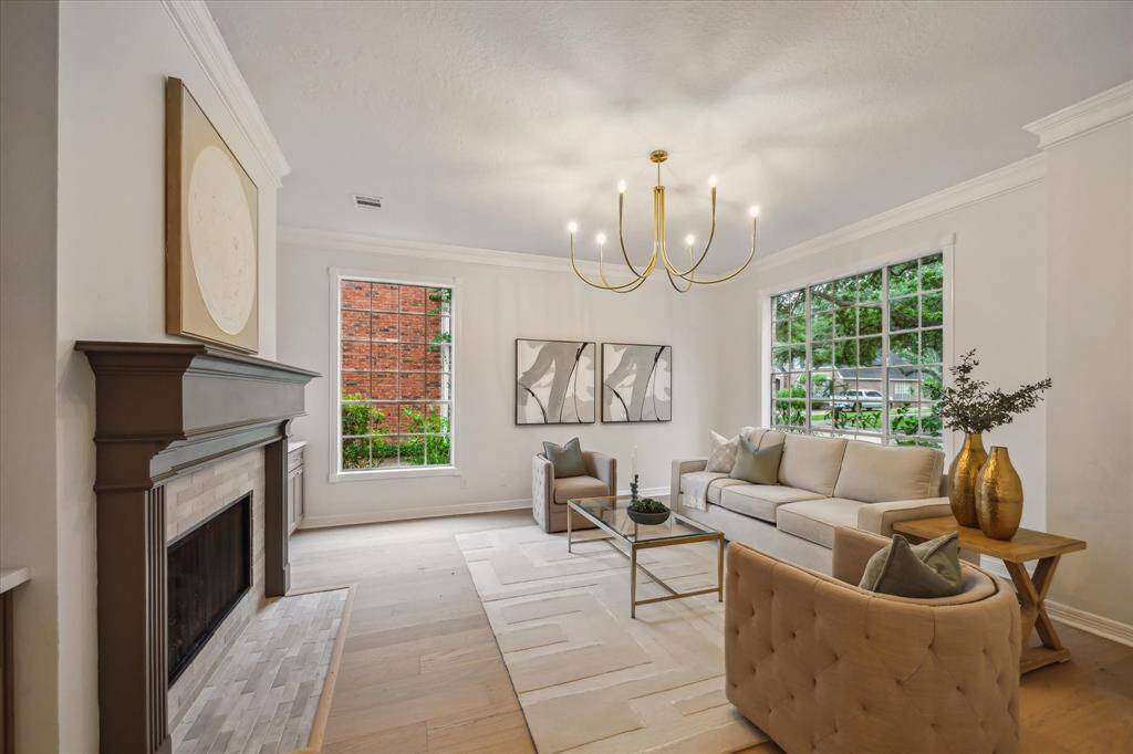 AN ELEGANT FORMAL LIVING ROOM TO YOUR RIGHT BOASTS A CHIC CHANDELIER, TILE SURROUND FIREPLACE, AND RICH CROWN MOLDING.
