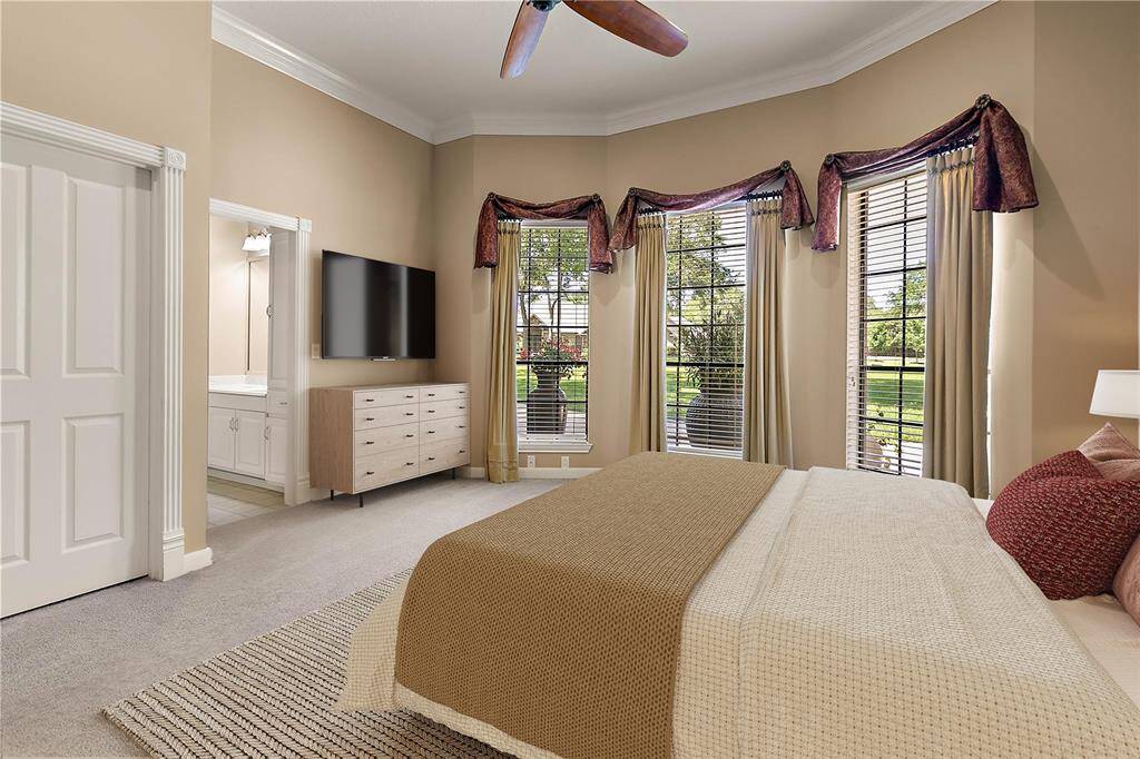 Secondary bedroom with neutral carpet, ceiling fan, and a spacious layout.
