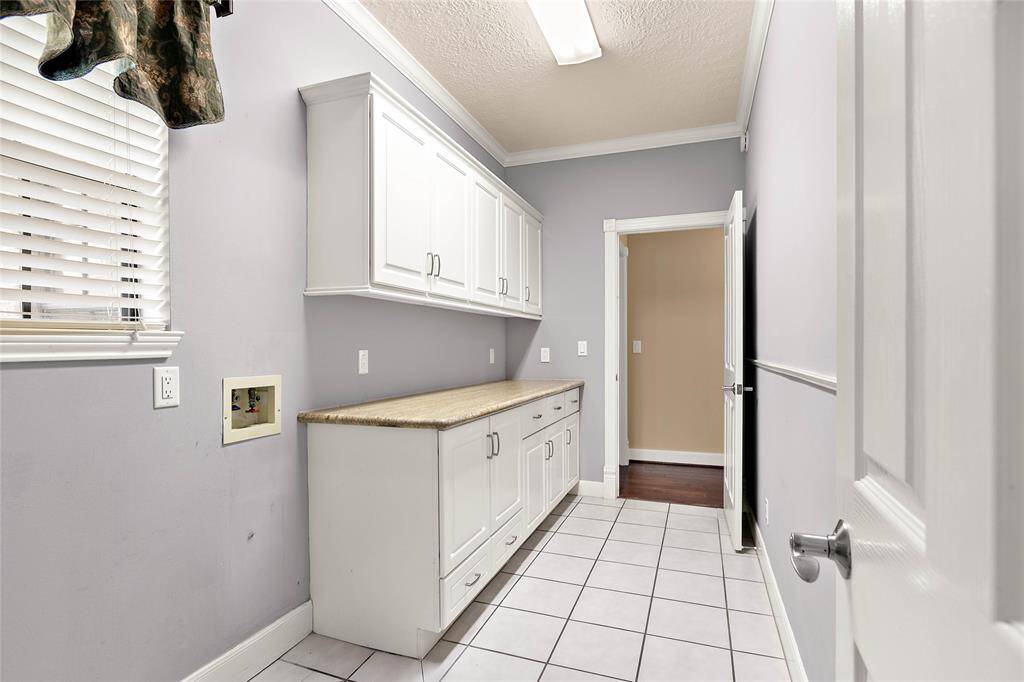 Huge laundry room with upper cabinetry and counter space for folding and extra storage.