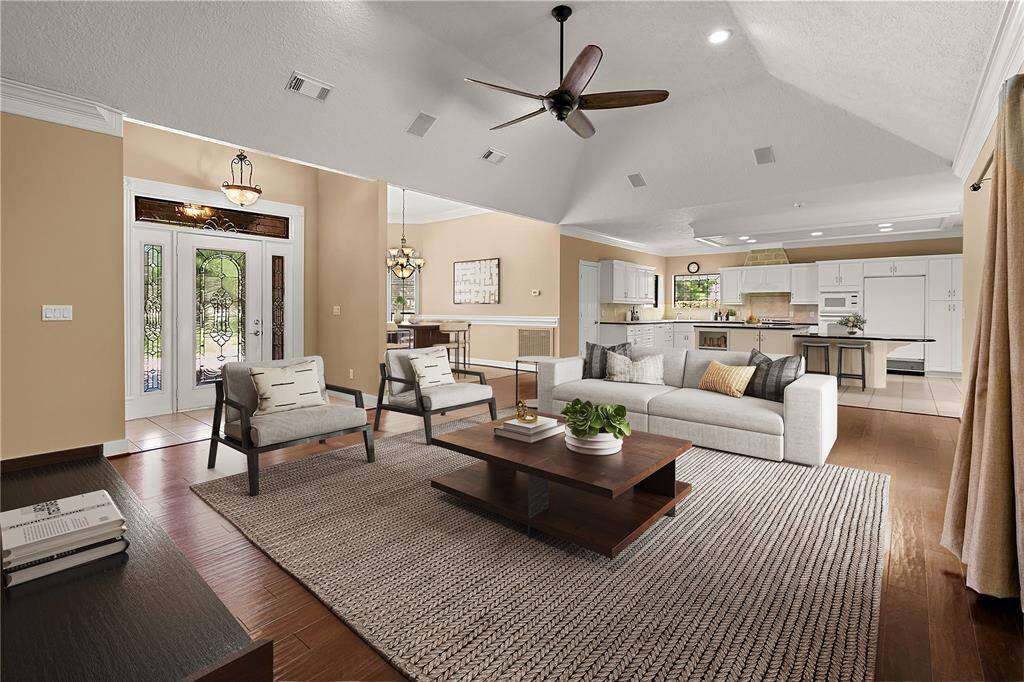 Spacious family room with high ceiling, hardwood floors, & recessed lighting opens to island kitchen and formal dining area.