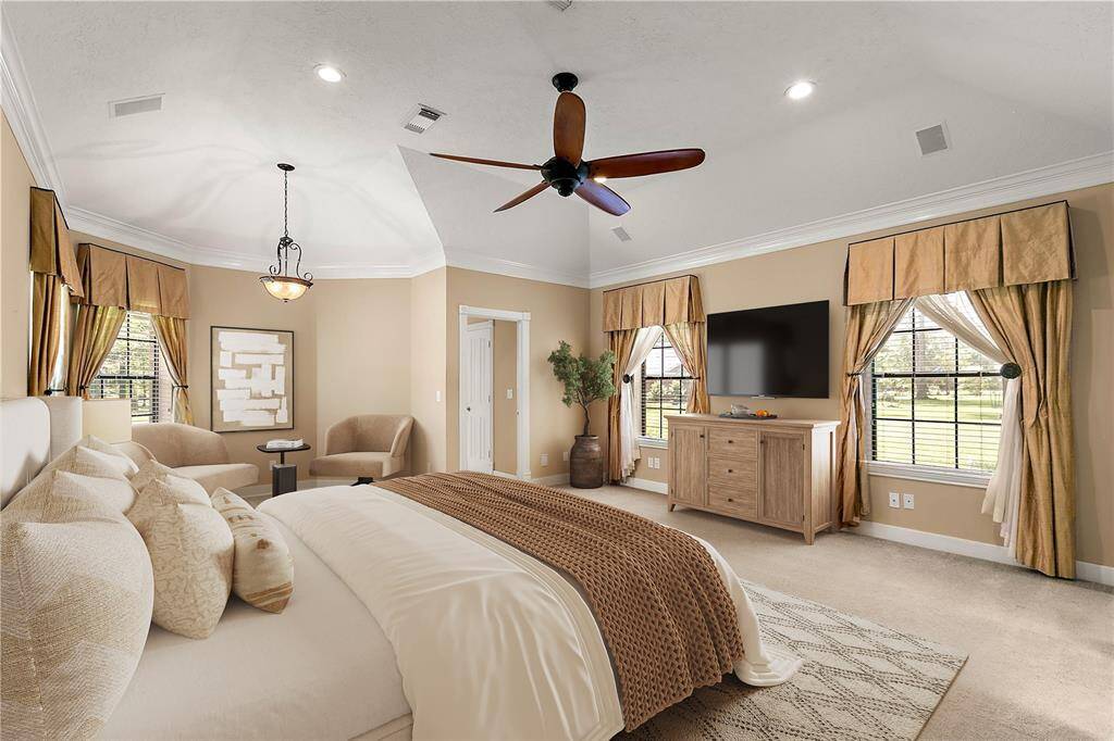 Elegant primary suite featuring vaulted ceilings, plush carpet, and sitting area with a view.