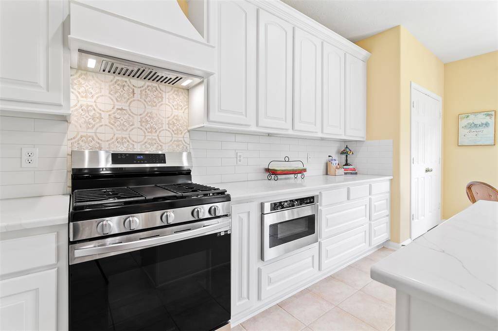 Kitchen features quartz countertops, subway tile backsplash and decorative backsplash behind the gas range.