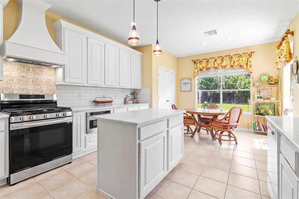 Large island in the middle has storage and pendant lighting.  Custom vent hood as well showcases this fabulous kitchen.