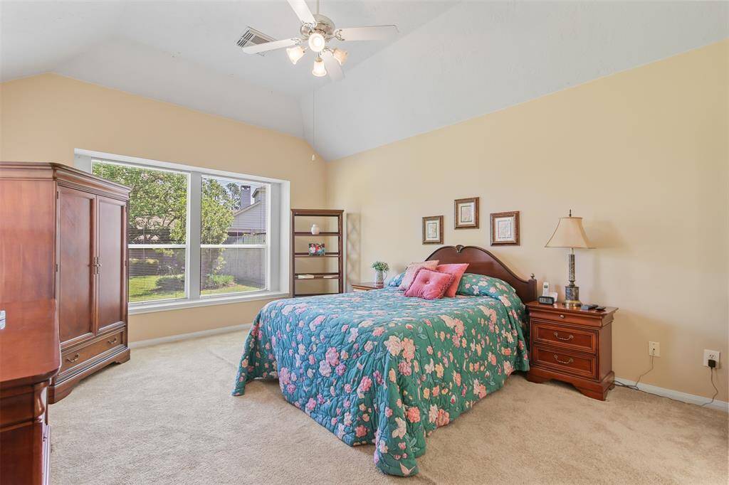 Primary bedroom has carpet, ceiling fan and large picture window overlooking the backyard.