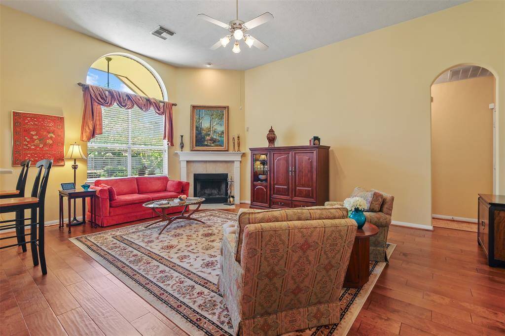 Family room has high ceilings, wood flooring and floor to wall window to allow for plenty of natural light. There is also a wood burning fireplace with tile surround and mantle.